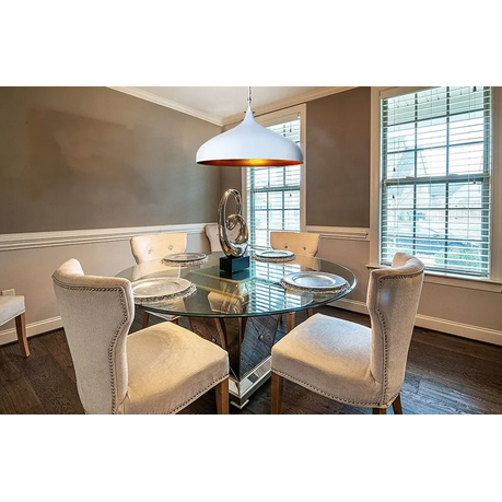Dining room with a glass table and upholstered chairs near a window.
